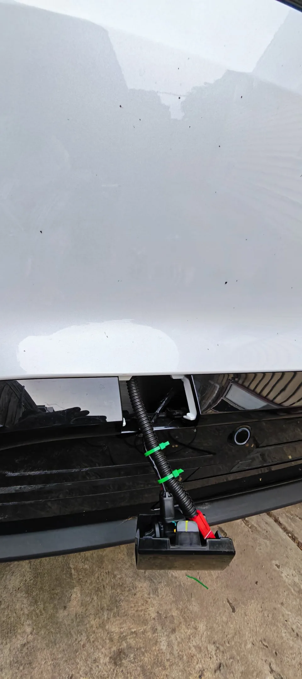 Additional owner photo of wiring and connectors behind the removed tow-hook cover