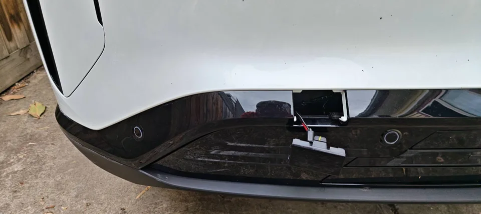 Front bumper tow-hook cover removed, with the emergency power connector exposed