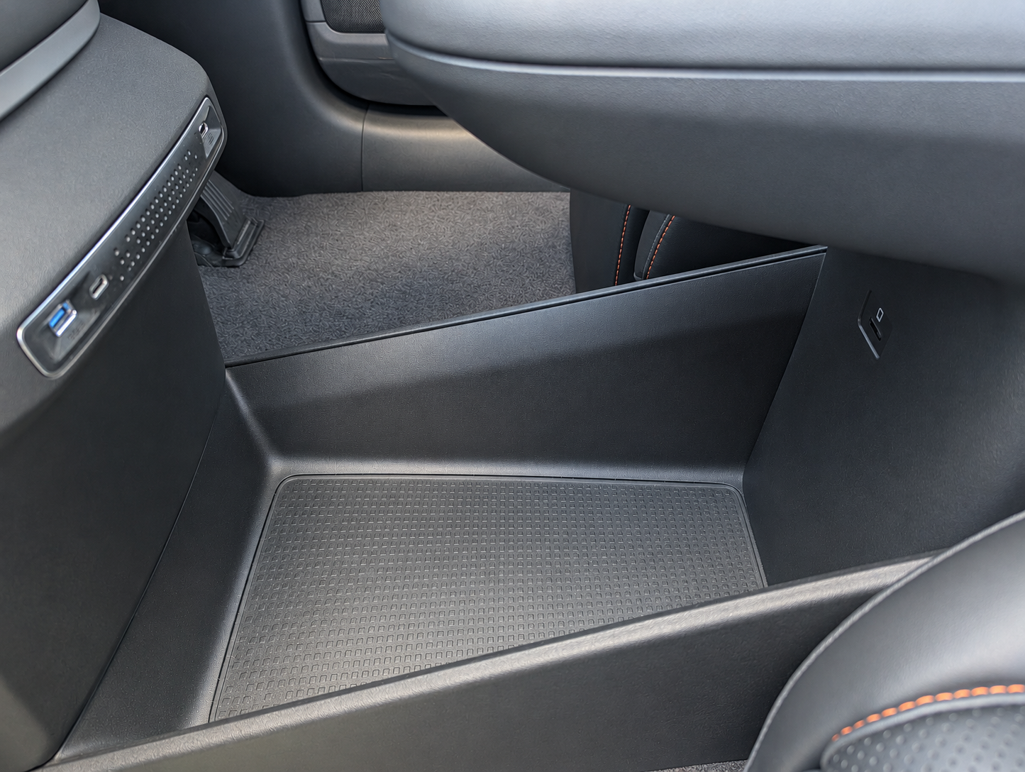 Lower centre-console storage area beneath the cupholders, showing the SD card slot on the inner right wall.